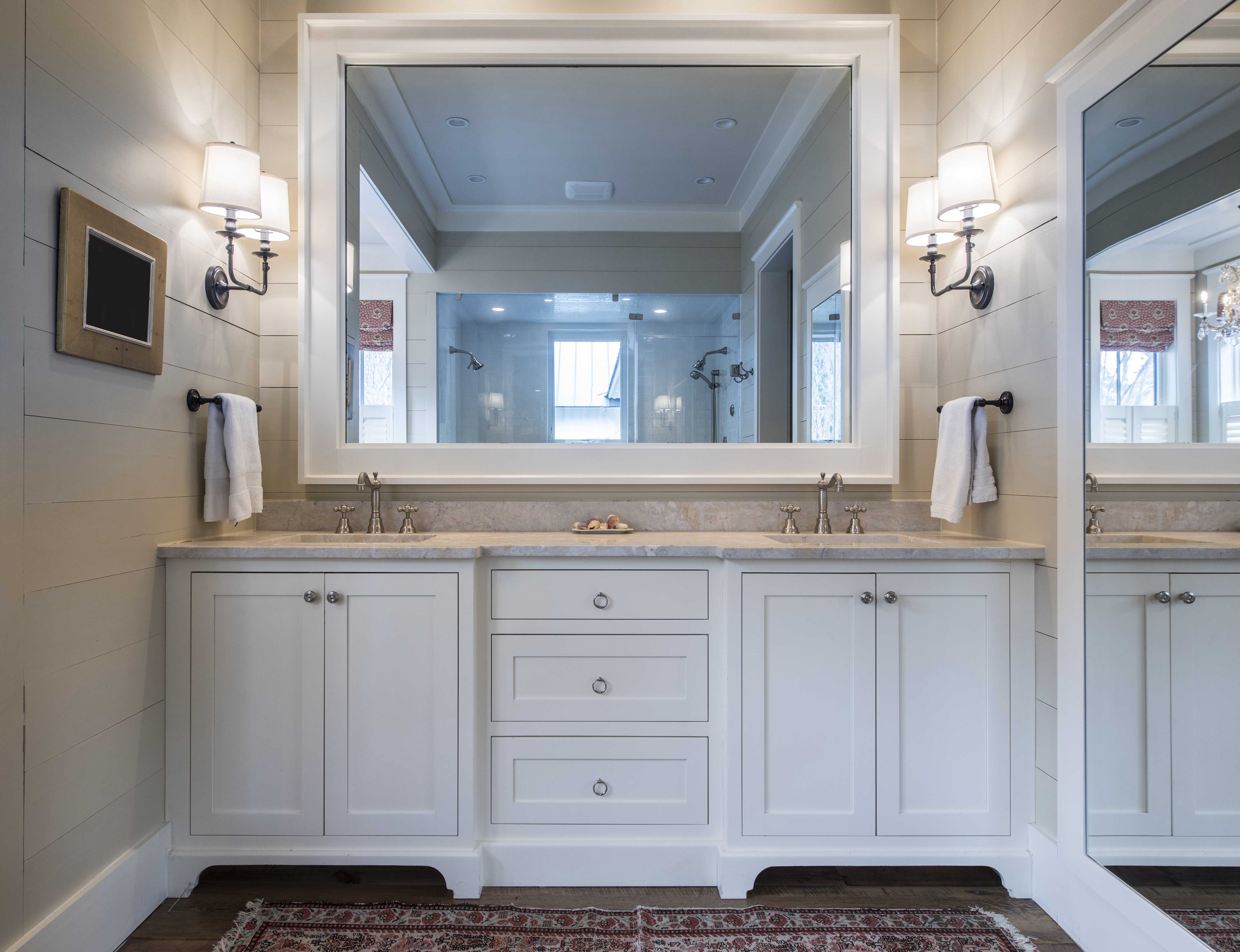 Bathroom vanity with double sinks, marble countertop, large mirrors, and gray shiplap walls